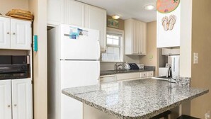 A modern kitchen with white cabinets, a granite countertop, and a built-in oven. - Red Robyn by Meyer Vacation Rentals (Gulf Shores)