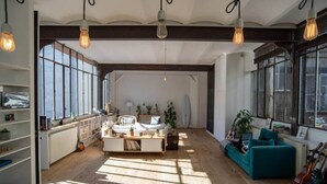 A spacious living room with a large window, a sofa, a coffee table, and a bookshelf. - La Fleur Loft Boutique Spa (Villa General Belgrano)