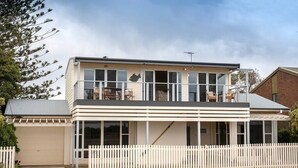 A two-story house with a balcony, a garage, and a white picket fence. - PORT WILLUNGA DREAMING a beach front experience (Port Willunga)