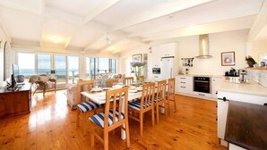 A spacious kitchen with a dining area, large windows, and a view of the sea. - PORT WILLUNGA DREAMING a beach front experience (Port Willunga)