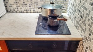 Una cucina con forno integrato, una pentola sul fornello e una padella su un tappetino resistente al calore.