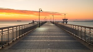Una lunga passeggiata rettilinea con balaustre su entrambi i lati, che conduce a una costa lontana.