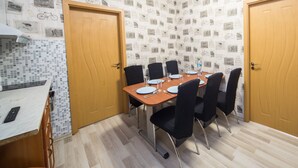 Una sala da pranzo con un tavolo di legno apparecchiato per quattro persone, circondato da sedie nere. La stanza presenta uno schienale a parete rivestito di piastrelle con decorazioni a tema bicicletta e due porte in legno.