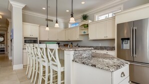 A modern kitchen with white cabinetry, a granite countertop, stainless steel appliances, and pendant lighting. - Fantastic Pet Friendly Multi Family Home w/ Pool (Hilton Head Island)