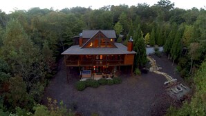 Eine große, zweistöckige Blockhütte, umgeben von dichtem Wald.
