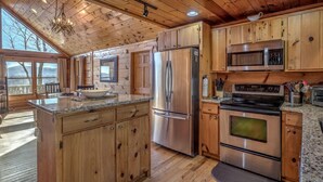 Une cuisine spacieuse dotée de meubles en bois, d’appareils électroménagers en acier inoxydable et d’un grand îlot central.