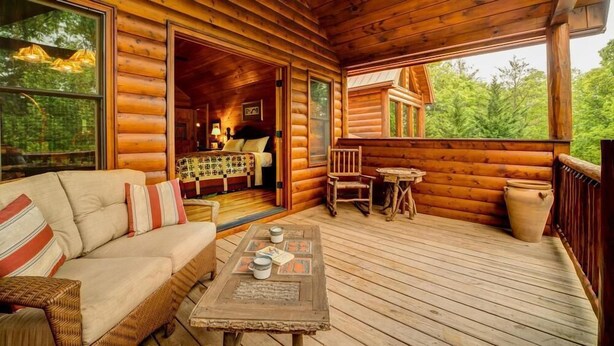Une cabane en rondins dotée d’un intérieur chaleureux, d’une terrasse en bois et offrant une vue sur la forêt environnante.
