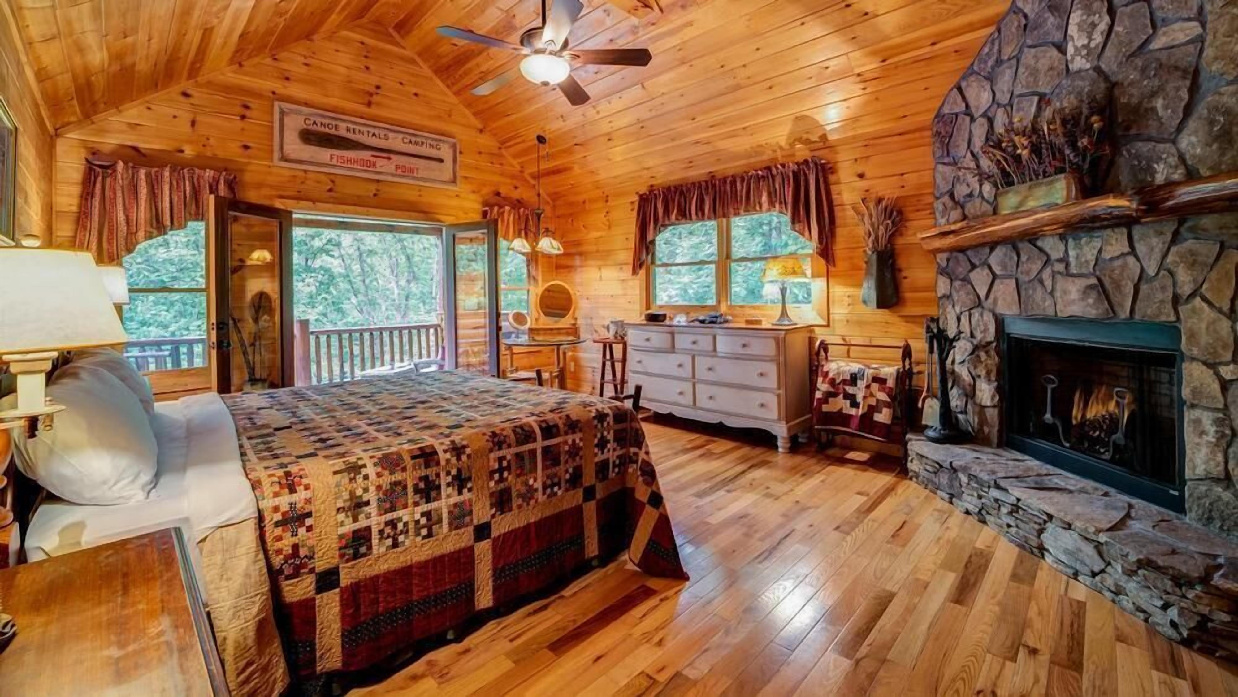 A cabin interior with a bed, dresser, vanity, and fireplace.