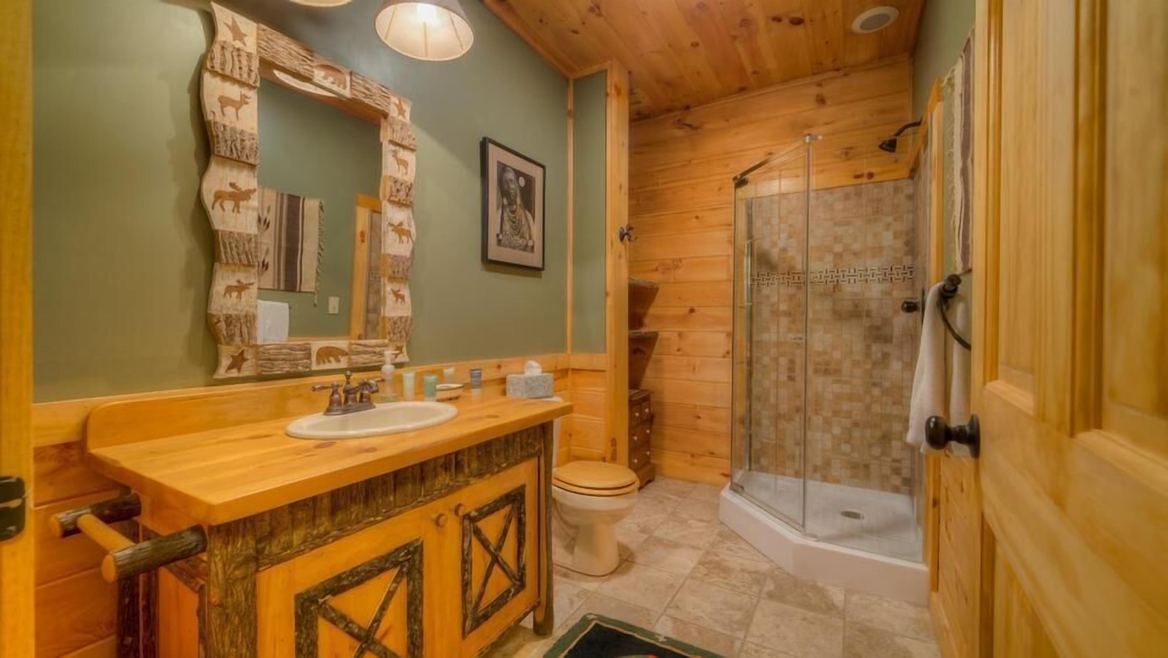 A wooden bathroom with a sink, toilet, and glass-enclosed shower.