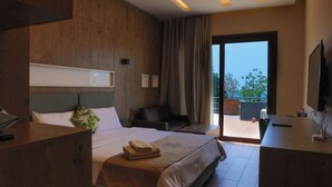 A modern hotel room with a large bed, wooden furniture, a desk, and a balcony with a view. - Haya hotel & spa (Tabarja)