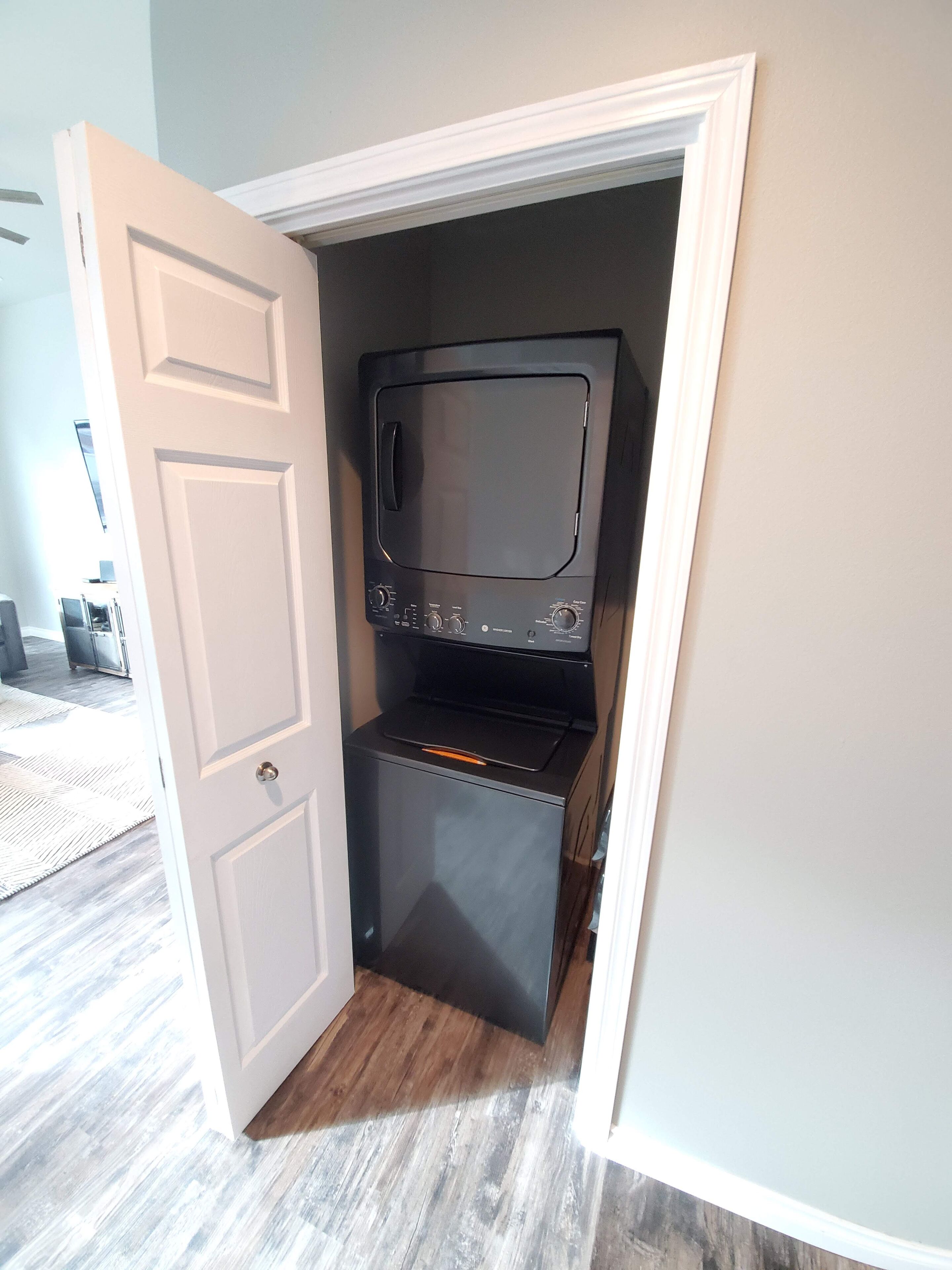 A compact kitchen with a microwave and oven, a white door, and a wooden floor.