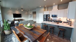 Une cuisine moderne avec des meubles blancs, un îlot central et des tabourets de bar.