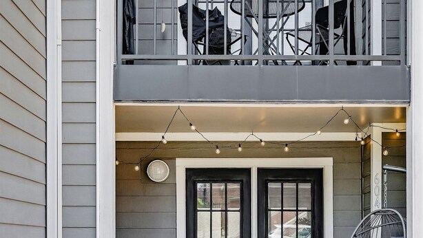 Ein zweistöckiges Haus mit Eingangstür, einer kleinen Terrasse mit Tisch und Stühlen sowie einer Hängematte.