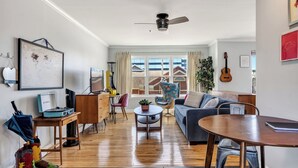 Ein Wohnzimmer mit Sofa, Esstisch, Fernseher und Deckenventilator.