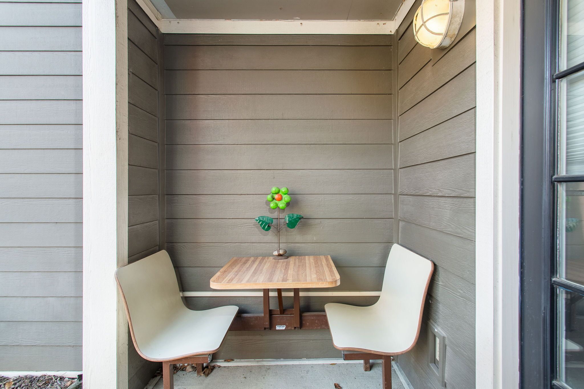 A small, enclosed patio area with a wooden table and two chairs.