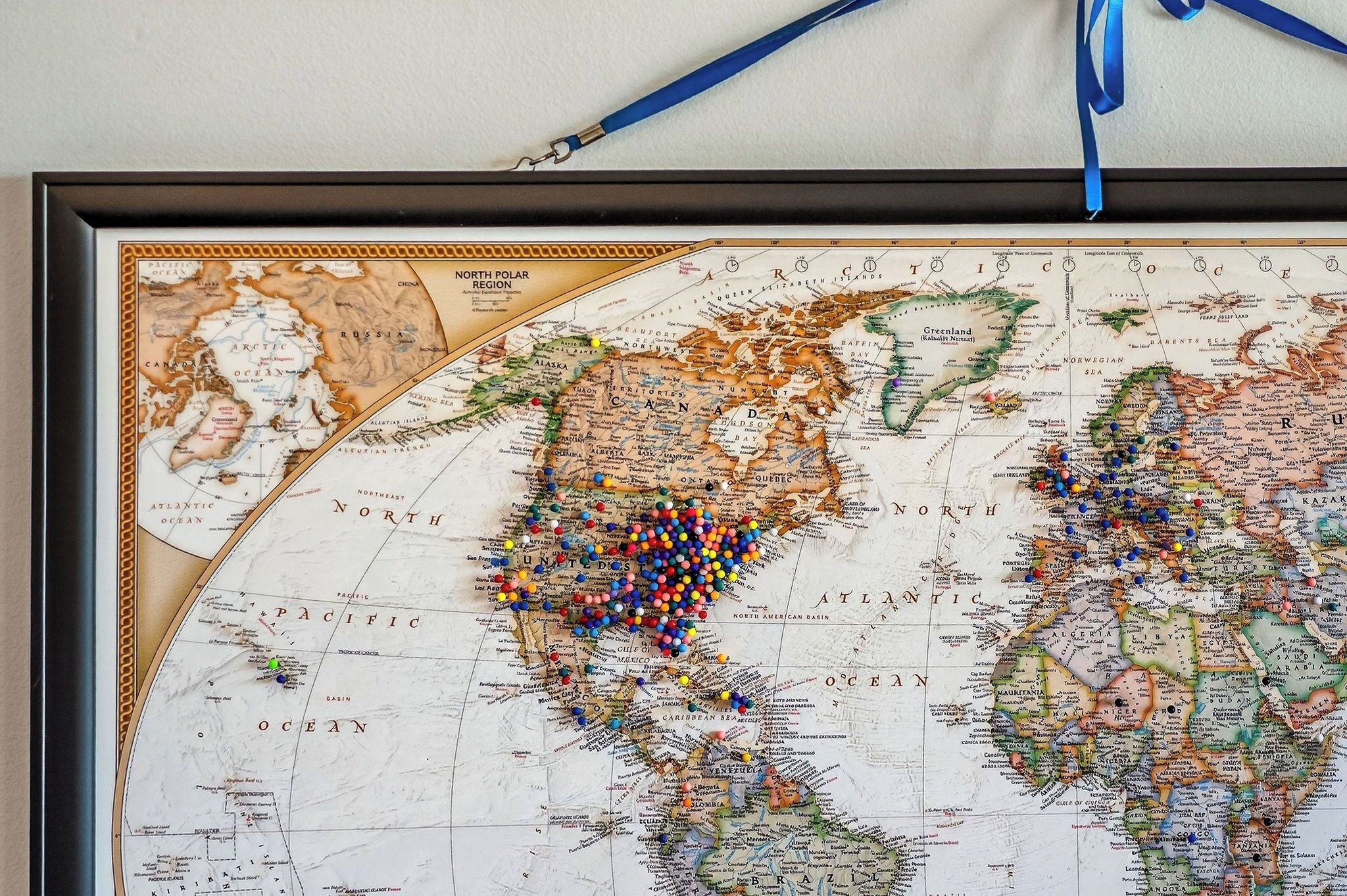 A framed world map with pins in various colors.