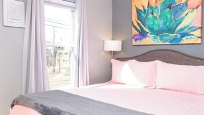 Ein Schlafzimmer mit einem Bett, einer Gitarre, einem Fenster und einem Gemälde.