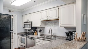 A kitchen with white cabinets, stainless steel appliances, granite countertops, and a coffee maker.