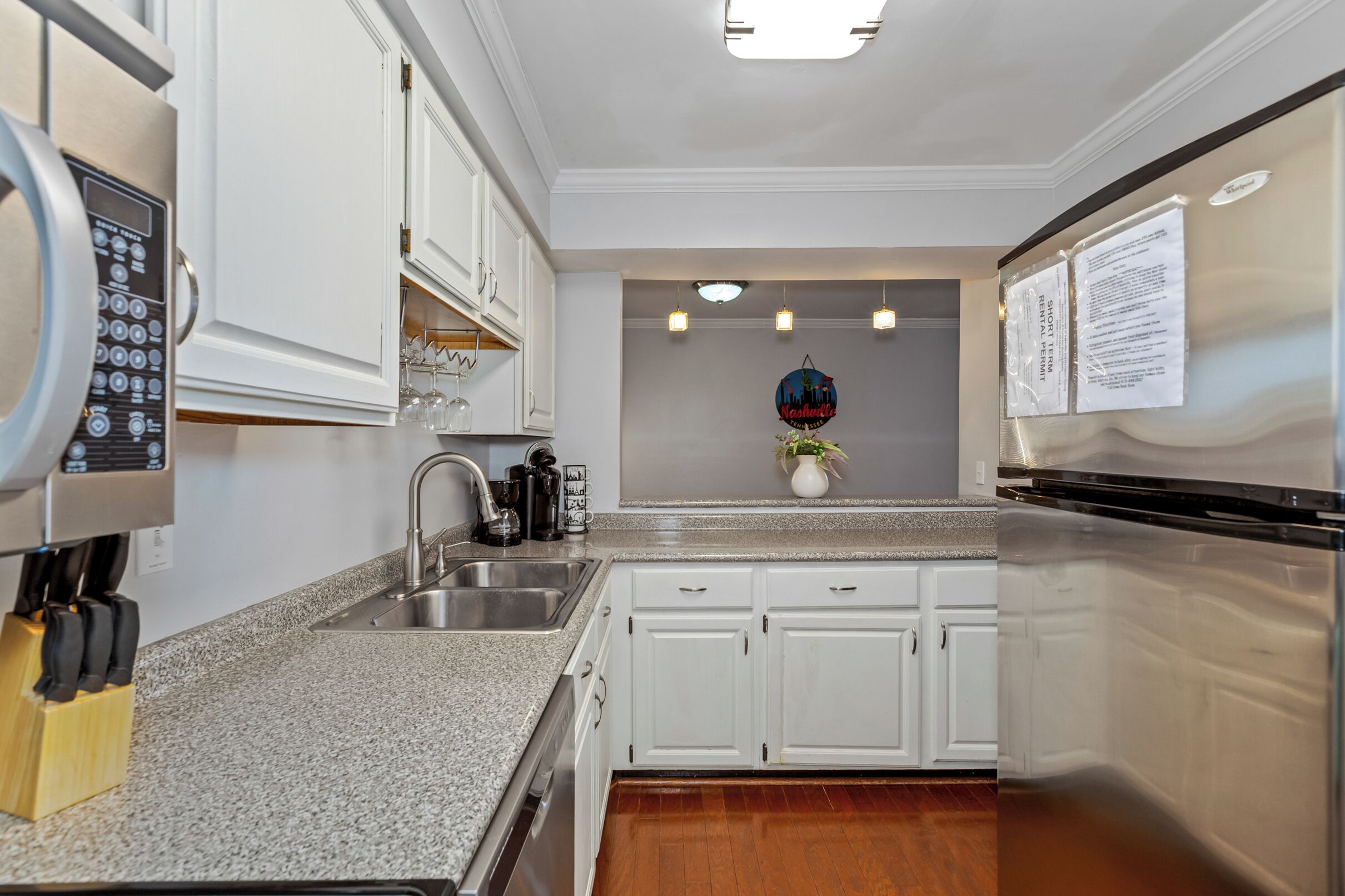 A modern kitchen with white cabinetry, a stainless steel sink, and a coffee maker.