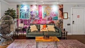 A modern living room with a green sofa, a wooden coffee table, and a vibrant abstract mural on the wall.