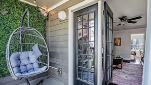 A room with a grey exterior wall, a hanging chair, a glass door, and a ceiling fan.
