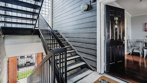 A modern interior with a staircase, a black door with a number, and a view of the outside.