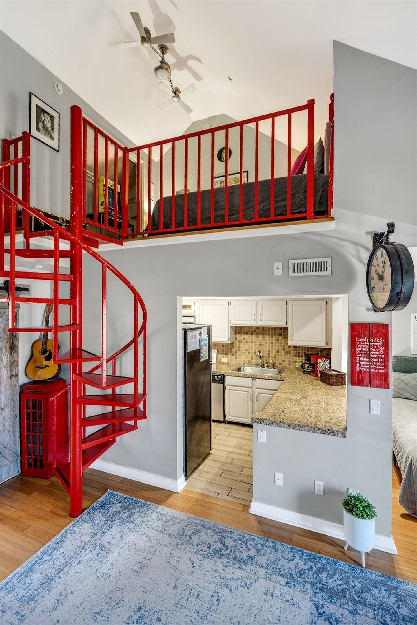 Interior de una vivienda con varios niveles, que incluye una escalera espiral roja, una zona de cocina y un espacio de estar.
