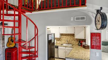 Interior de una vivienda con varios niveles, que incluye una escalera espiral roja, una zona de cocina y un espacio de estar.