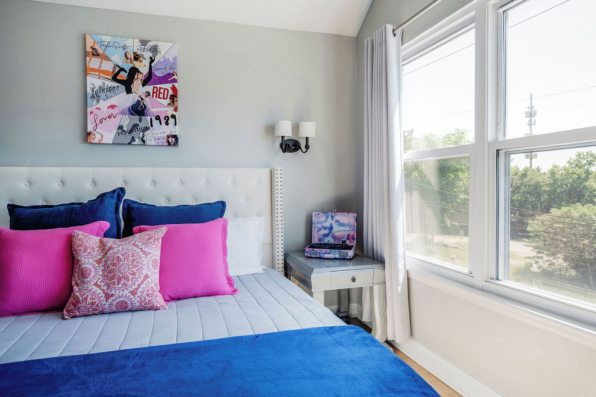 A bedroom with a bed, pillows, a nightstand, a lamp, and a window.