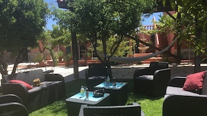 An outdoor seating area with wicker furniture, a hammock, and a stone pathway.