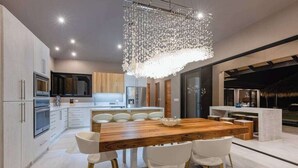 A modern kitchen with a central island, white cabinetry, and a hanging light fixture.
