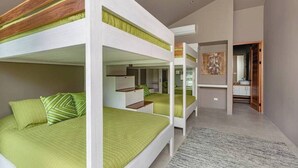 A modern interior with bunk beds, a kitchen area, and a hallway leading to a bathroom.