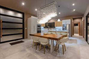 A modern kitchen with a central island, white cabinetry, and a hanging light fixture.