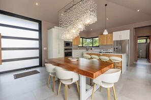 A modern kitchen with a central island, white cabinetry, and a unique chandelier.