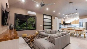 A modern living room with a sofa, a wooden coffee table, and a dining area with a table and chairs.