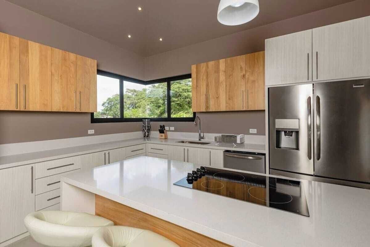 A modern kitchen with a large island, stainless steel appliances, and wooden cabinetry.