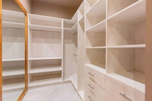 A walk-in closet with open shelving and drawers.