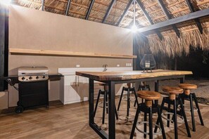 An outdoor kitchen area with a gas stove, a sink, and bar stools.