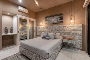 A bedroom with a bed, a wardrobe, a mirror, and a wall-mounted shelf.