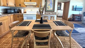 A dining area with a wooden table and chairs, a microwave, stove, and a framed map on the wall. - Old Goat Inn, Wonderful Cottage on Flathead Lake (Somers)