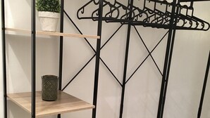 Una estantería de madera escalonada con estructura metálica, un perchero y una pequeña planta en maceta.