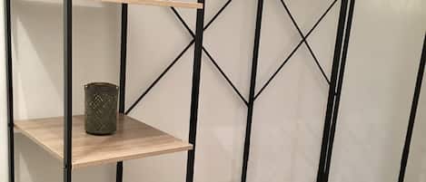 Una estantería de madera escalonada con estructura metálica, un perchero y una pequeña planta en maceta.