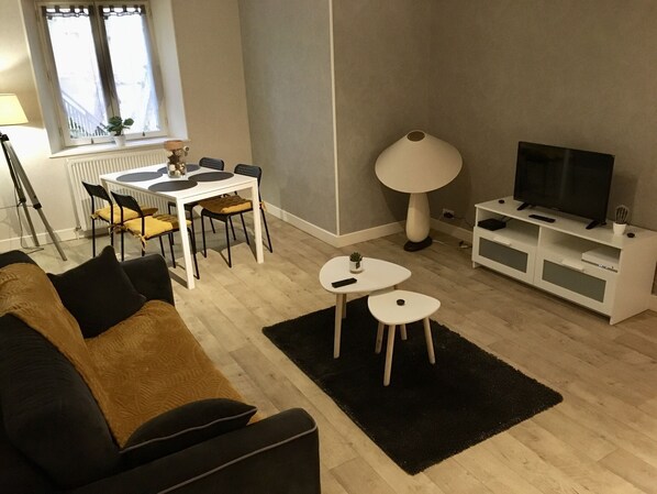 A modern living room with a sofa, a dining table with chairs, a TV stand, and a lamp. - ** ANY COMFORT WITH PRIVATE TERRACE AND GARDEN ** (Guéret)
