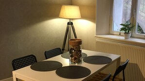 Una mesa de comedor con cuatro sillas, una lámpara y un jarrón decorativo.