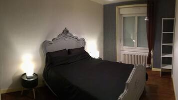 A bedroom with a bed, bedside lamp, and a window with curtains.