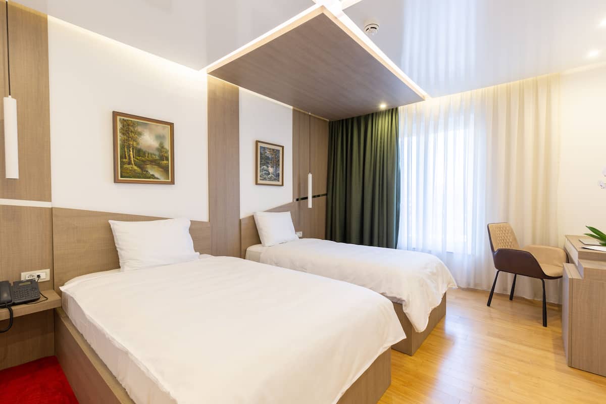 Een hotelkamer met twee bedden, een bureau, een stoel en een telefoon op een nachtkastje.