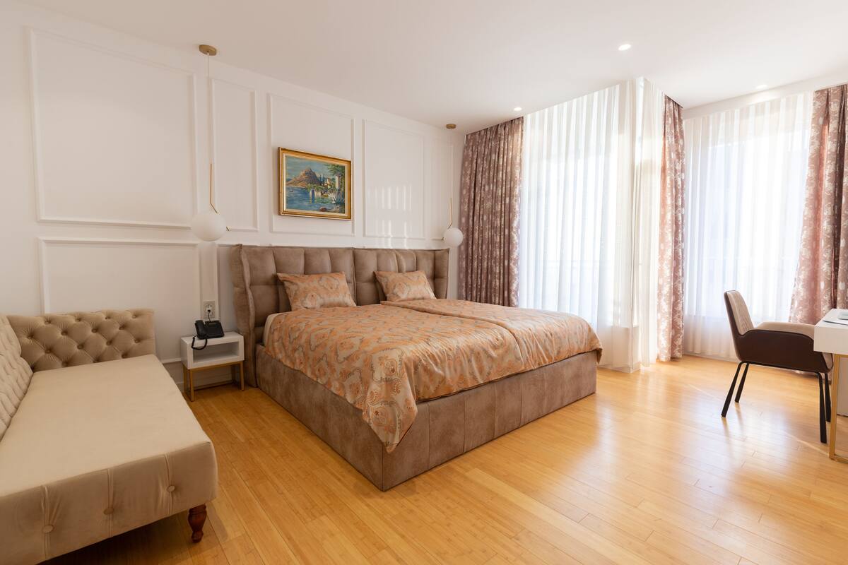 Een slaapkamer met een groot bed, een nachtkastje, een stoel en een bureau.