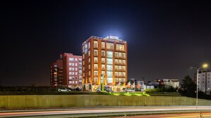 A hotel with a prominent sign, multiple floors, and a parking area with cars. - Star Hill Hotel & SPA (Pristina)