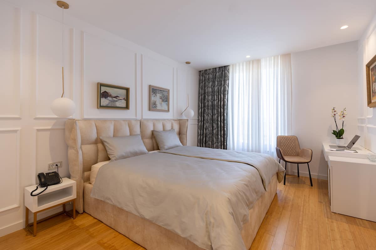 Een moderne slaapkamer met een groot bed, nachtkastjes, een bureau met stoel en kunst aan de muren.