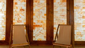 A room with a wooden floor and a large window with a patterned view. There are two canvas chairs in the room. - Star Hill Hotel & SPA (Pristina)